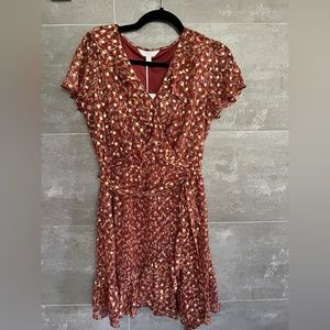 Women’s ruffle dress with tie and gold accents.